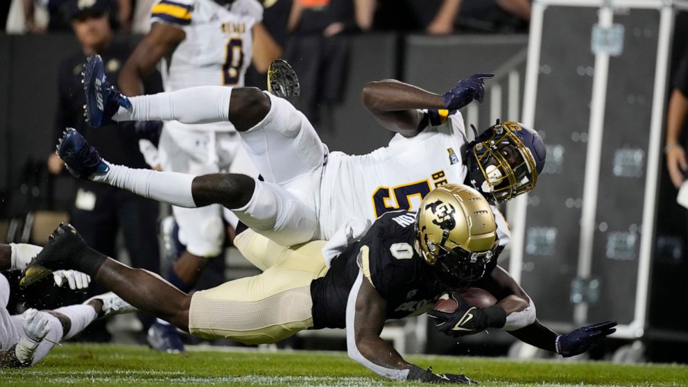 File—Colorado running back Ashaad Clayton, front, tumbles to the turf after being tripped by Northern Colorado defensive back Komotay Koffie during the second half of an NCAA college football game in this file photograph taken Friday, Sept. 3, 2021, 