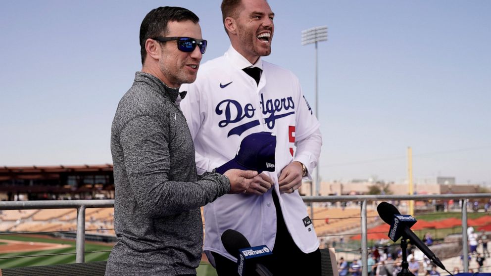 Los Angeles Dodgers president of baseball operations Andrew Friedman, left, announces the arrival of free agent Freddie Freeman during a news conference at spring training baseball, Friday, March 18, 2022, in Glendale, Ariz. (AP Photo/Charlie Riedel)