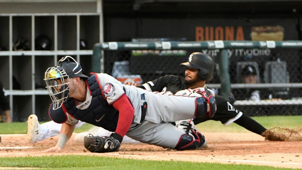 Chicago White Sox's Jose Rondon, back, is safe at home as Minnesota Twins catcher Mitch Garver, front, can't handle an errant throw during the second inning of a baseball game, Saturday, July 27, 2019, in Chicago. (AP Photo/David Banks)