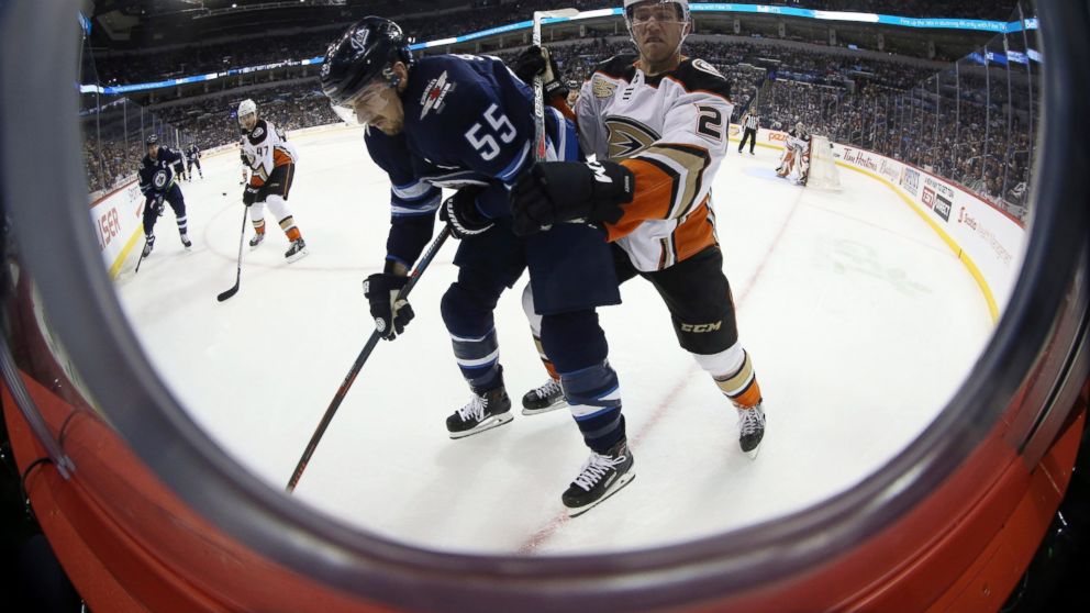 Anaheim Ducks' Carter Rowney (24) checks Winnipeg Jets' Mark Scheifele (55) during second-period NHL hockey game action in Winnipeg, Manitoba, Sunday, Jan. 13, 2019. (Trevor Hagan/The Canadian Press via AP)