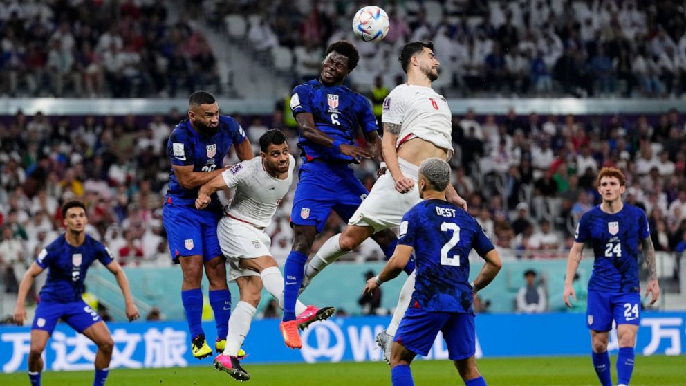 Players fight for a header during the World Cup group B soccer match between Iran and the United States at the Al Thumama Stadium in Doha, Qatar, Tuesday, Nov. 29, 2022. (AP Photo/Manu Fernandez)