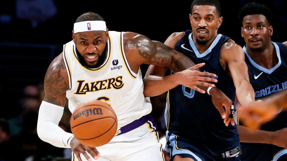 Los Angeles Lakers forward LeBron James, left, and Memphis Grizzlies guard De'Anthony Melton chase the ball during the second half of an NBA basketball game in Los Angeles, Sunday, Oct. 24, 2021. The Lakers won 121-118. (AP Photo/Ringo H.W. Chiu)