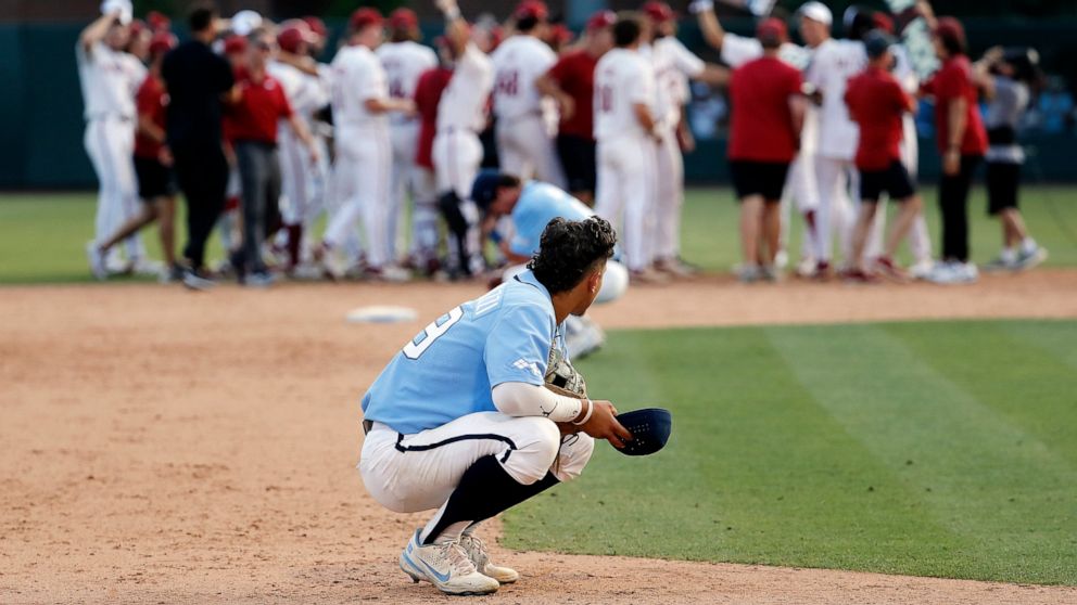 North Carolina's Johnny Castagnozzi (19) reacts as Arkansas celebrates in the background following an NCAA college super regional baseball game in Chapel Hill, N.C., Sunday, June 12, 2022. (AP Photo/Karl B DeBlaker)