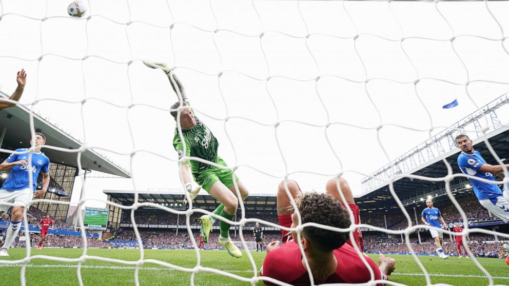 Everton's goalkeeper Jordan Pickford saves a ball as Liverpool's Roberto Firmino falls in the net during the English Premier League soccer match between Everton and Liverpool at Goodison Park, Liverpool, England, Saturday, Sept. 3, 2022. (AP Photo/Jo