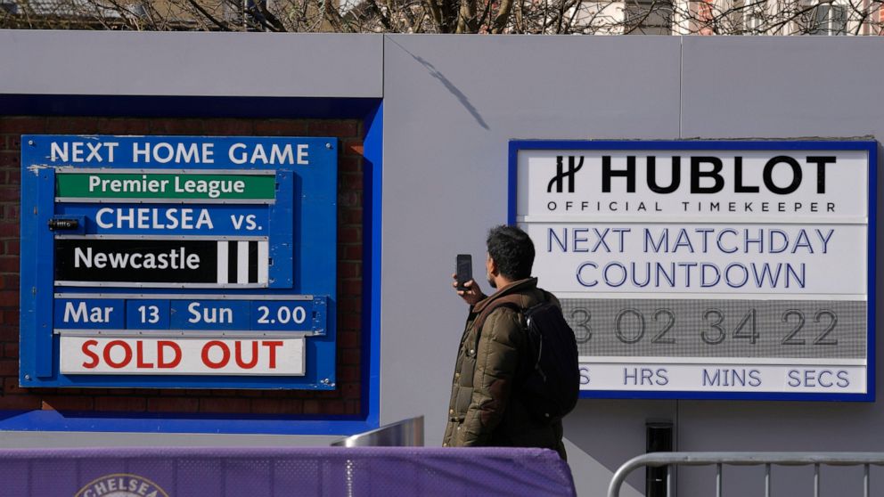 A fan takes a picture of a sign at Chelsea football club's Stamford Bridge stadium in London, Thursday, March 10, 2022. Unprecedented restrictions have been placed on Chelsea’s ability to operate by the British government after owner Roman Abramovich