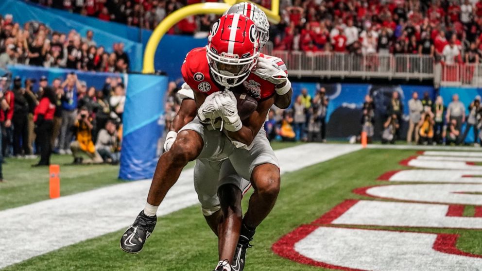 Georgia wide receiver Adonai Mitchell (5) makes a touchdown catch against Ohio State cornerback Denzel Burke (10) during the second half of the Peach Bowl NCAA college football semifinal playoff game, Saturday, Dec. 31, 2022, in Atlanta. (AP Photo/Br