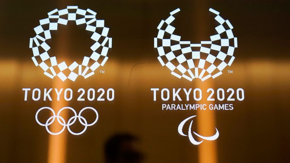 FILE - In this June 11, 2019, file photo, a man walks past the logos of the Tokyo 2020 Paralympics and Olympics in Tokyo. Ticket demand for the Tokyo Paralympics is at record levels. The unprecedented demand follows a similar surge in interest for th