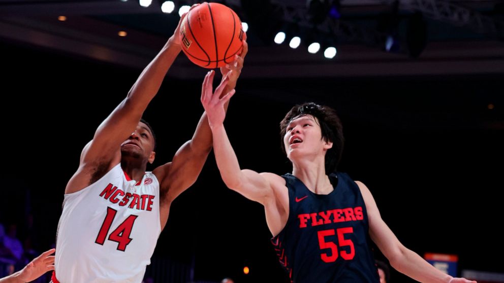 In a photo provided by Bahamas Visual Services, North Carolina State's Casey Morsell (14) grabs the ball ahead of Dayton's Mike Sharavjamts (55) during an NCAA college basketball game in the Battle 4 Atlantis at Paradise Island, Bahamas, Thursday, No