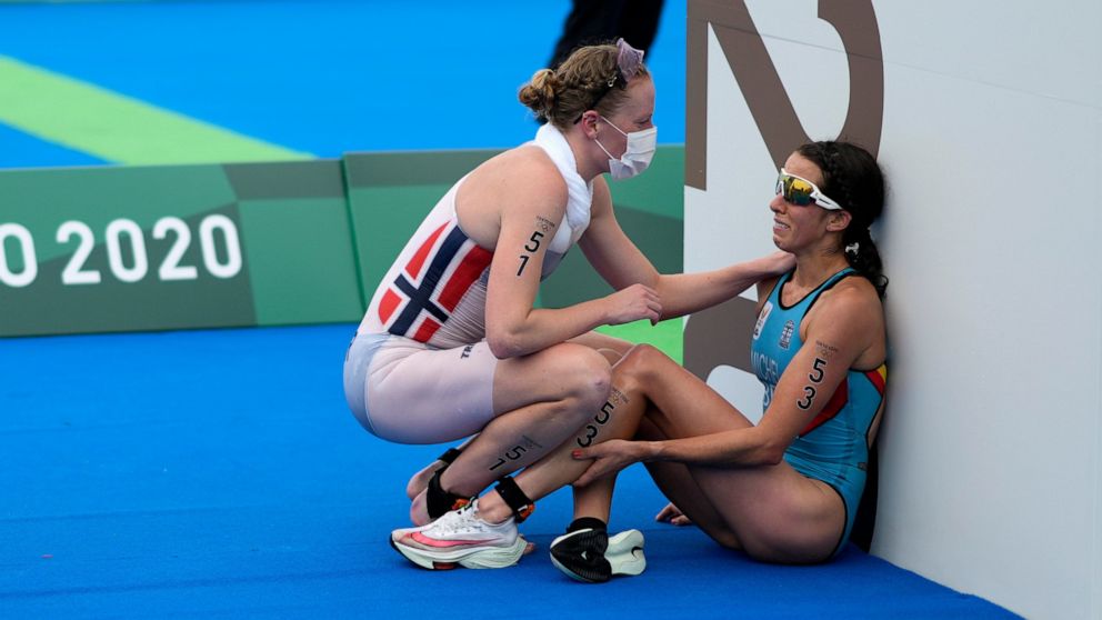 FILE - In this July 27, 2021, file photo, Claire Michel of Belgium is assisted by Lotte Miller of Norway after the finish of the women's individual triathlon competition at the 2020 Summer Olympics, in Tokyo, Japan. In an extraordinary Olympic Games 