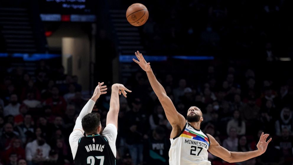 Portland Trail Blazers center Jusuf Nurkic, left, hits a shot over Minnesota Timberwolves center Rudy Gobert during the first half of an NBA basketball game in Portland, Ore., Saturday, Dec. 10, 2022. (AP Photo/Steve Dykes)