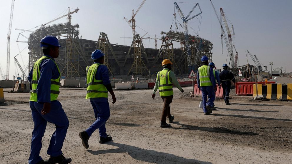 FILE - Workers walk to the Lusail Stadium, one of the 2022 World Cup stadiums, in Lusail, Qatar, Friday, Dec. 20, 2019. The eight stadiums for the World Cup, all within a 30-mile radius of Doha, are now largely complete. Migrant laborers who built Qa