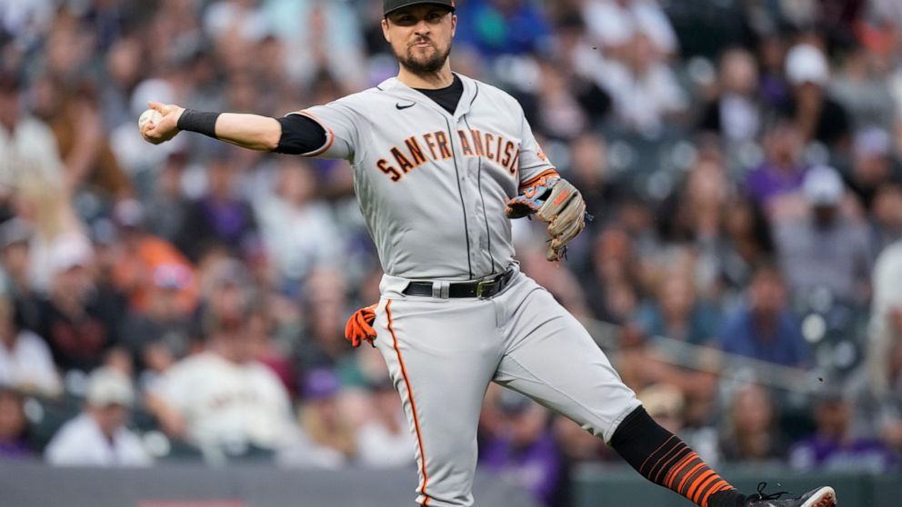 San Francisco Giants third baseman J.D. Davis throws to first base to put out Colorado Rockies' Brian Serven in the third inning of a baseball game against the Saturday, Aug. 20, 2022, in Denver. (AP Photo/David Zalubowski)