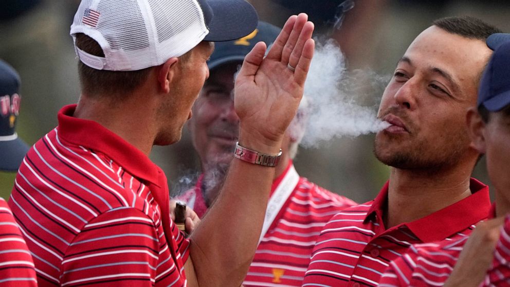 FILE - Xander Schauffele blows smoke toward Jordan Spieth after the USA team defeated the International team in a singles match at the Presidents Cup golf tournament at the Quail Hollow Club, Sunday, Sept. 25, 2022, in Charlotte, N.C. Schauffele ende