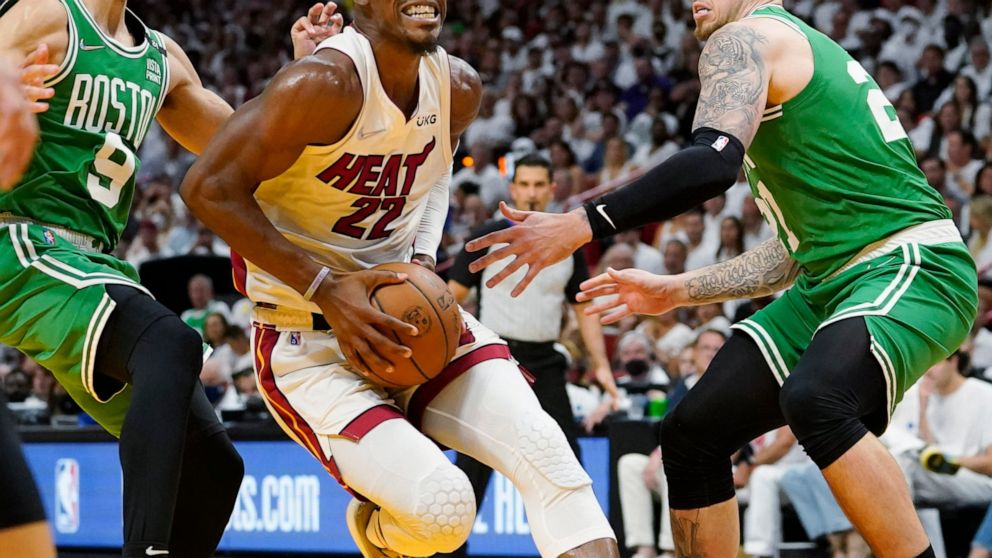 Miami Heat forward Jimmy Butler (22) drives to the basket between Boston Celtics guard Derrick White (9) and center Daniel Theis (27) during the second half of Game 1 of an NBA basketball Eastern Conference finals playoff series, Tuesday, May 17, 202