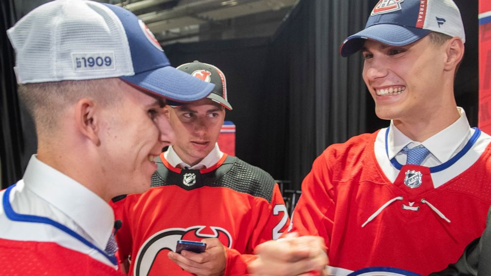 Juraj Slafkovsky, right, of Slovakia, greets countryman and fellow Montreal Canadiens draft pick Filip Mesar, left, as Simon Nemec, also from Slovakia and a New Jersey Devils pick, looks on during the first round of the NHL hockey draft in Montreal o