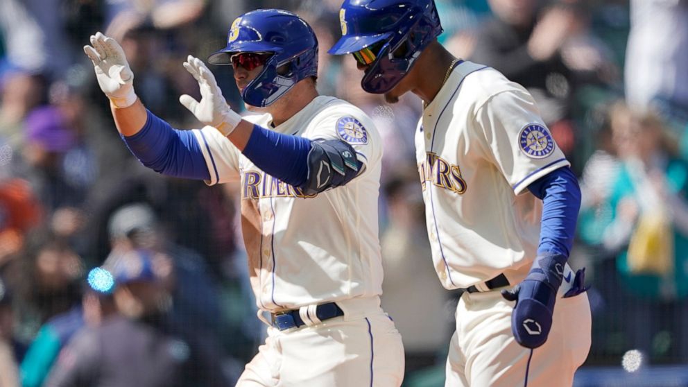 Seattle Mariners' Ty France left, reacts with Julio Rodriguez, right, after France hit a three-run home run to score Rodriguez and Adam Frazier during the fourth inning of a baseball game against the Houston Astros, Sunday, April 17, 2022, in Seattle