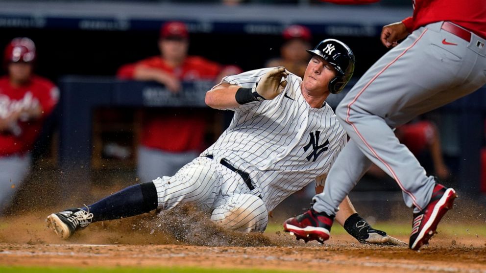 New York Yankees' DJ LeMahieu slides past Cincinnati Reds pitcher Alexis Diaz to score on a wild pitch during the 10th inning of a baseball game Wednesday, July 13, 2022, in New York. The Yankees won 7-6. (AP Photo/Frank Franklin II)