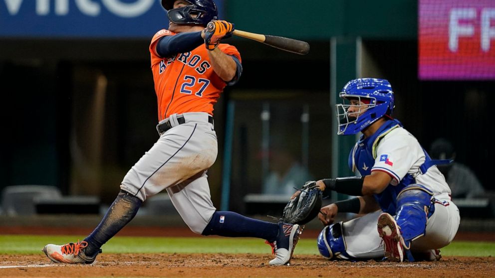 Houston Astros' Jose Altuve follows through on a two RBI double in the second inning of a baseball game as Texas Rangers catcher Meibrys Viloria looks on in Arlington, Texas, Wednesday, Aug. 31, 2022. The hit scored Mauricio Dubon and David Hensley. 