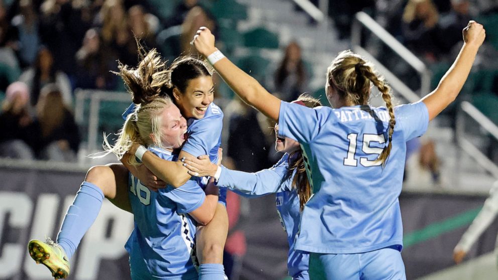 North Carolina's Aleigh Gambone (16) is congratulated on her goal against Florida State by Tori Dellaperuta, as teammates gather during the first half of an NCAA women's soccer tournament semifinal in Cary, N.C., Friday, Dec. 2, 2022. (AP Photo/Karl 