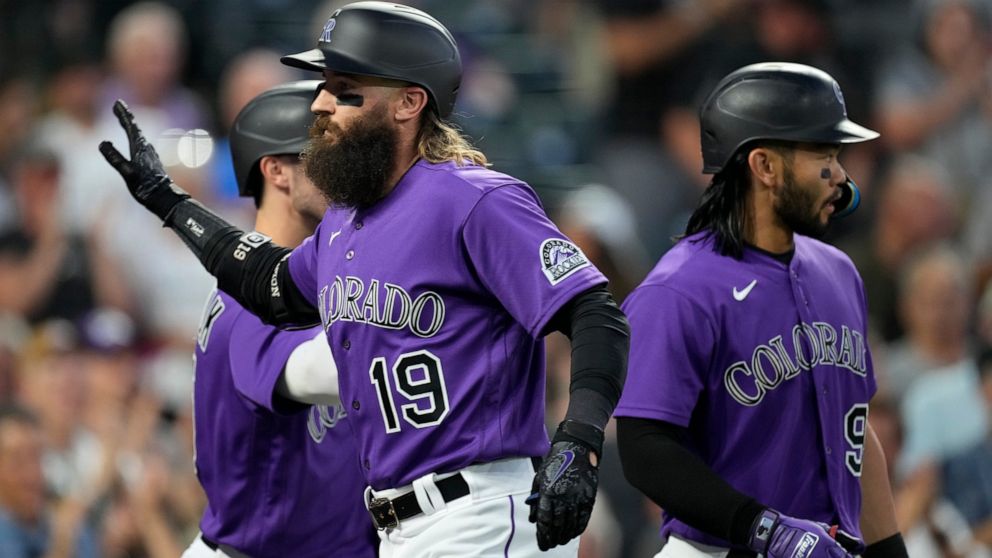 Colorado Rockies' Charlie Blackmon, front, is congratulated, after hitting a three-run home run, by Randal Grichuk, left, and Connor Joe during the sixth inning of the team's baseball game against the San Diego Padres on Tuesday, July 12, 2022, in De