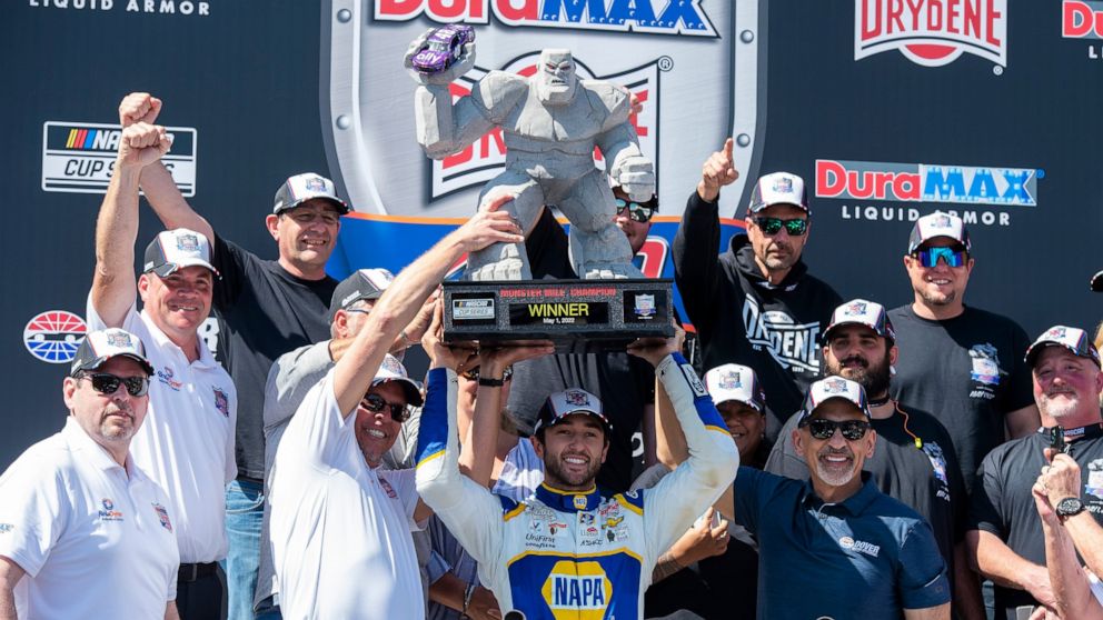 Chase Elliott, center, holds up his trophy after a NASCAR Cup Series auto race at Dover Motor Speedway, Monday, May 2, 2022, in Dover, Del. (AP Photo/Jason Minto)