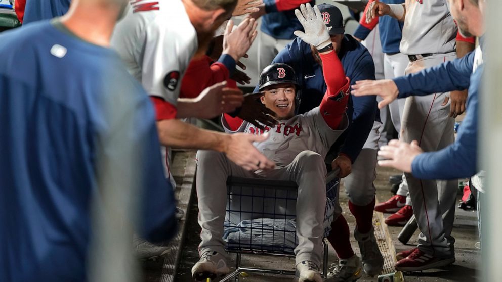 Boston Red Sox's Bobby Dalbec is pushed trough the dugout in a towel cart by Kevin Plawecki after Dalbec hit a solo home run during the seventh inning of the team's baseball game against the Seattle Mariners, Friday, June 10, 2022, in Seattle. (AP Ph