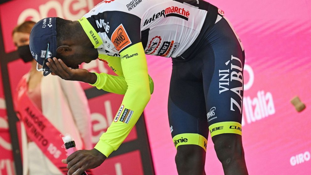 Eritrea's Biniam Girmay touches his eye after spraying sparkling wine on the podium to celebrate winning the 10th stage of the Giro D'Italia cycling race from Pescara to Jesi, Italy, Tuesday, May 17, 2022. Girmay was then taken to a local hospital af