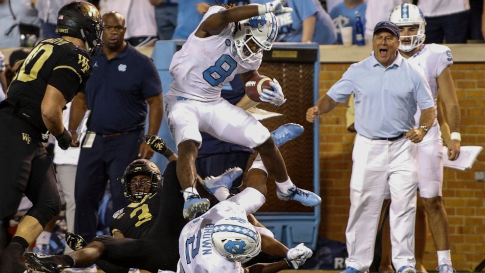 North Carolina running back Michael Carter (8) leaps over Wake Forest defensive back Nasir Greer (3) and North Carolina wide receiver Dyami Brown (2) during the second half of an NCAA college football game in Winston-Salem, N.C., Friday, Sept. 13, 20