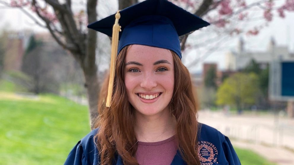 In this photo provided by Bailie Brown, Bailie Brown poses in the cap and gown she'll wear at graduation in Syracuse, N.Y., in this April 2021 photo. Brown doesn't consider herself a trailblazer, and yet in a way she is — and so is her school. In lat