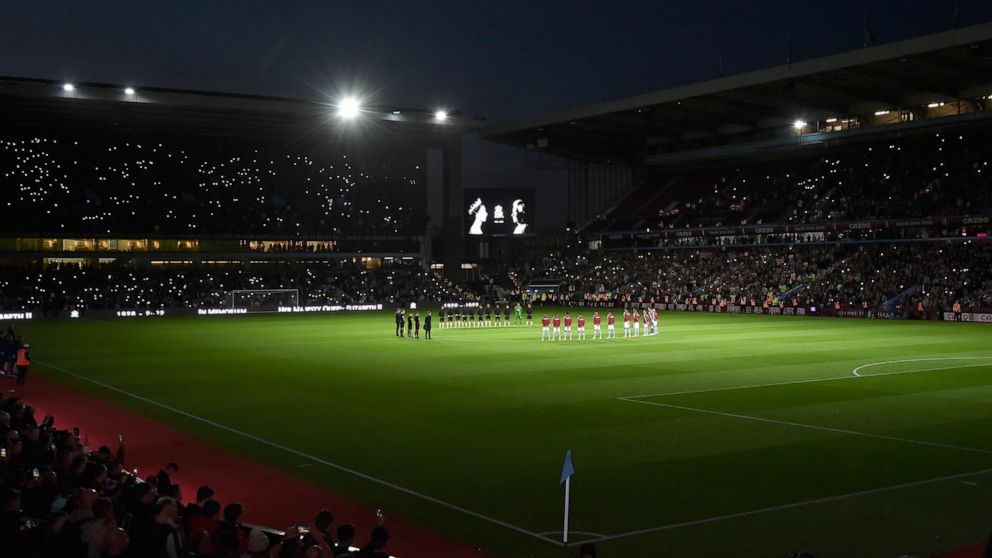 Players stand on the center of the pitch during a moment of silence tribute to Queen Elizabeth II before the English Premier League soccer match between Aston Villa and Southampton at Villa Park in Birmingham, England, Friday, Sept. 16, 2022. (AP Pho