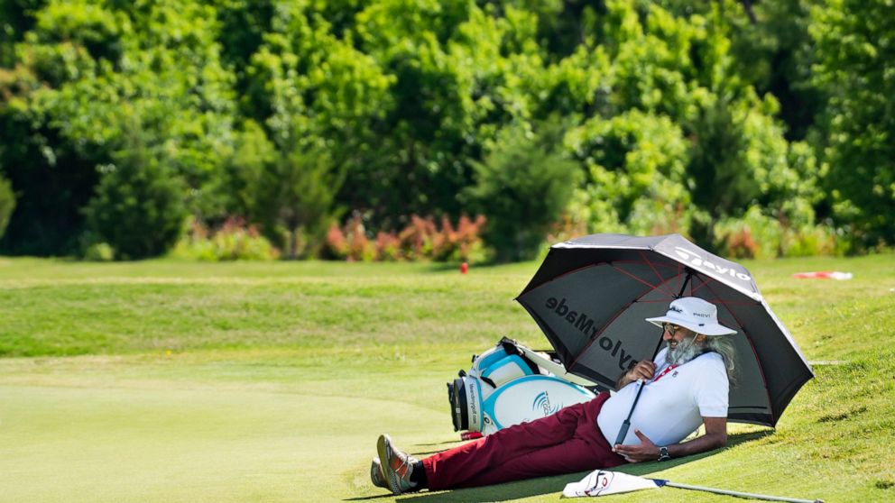 A spectator relaxes under an umbrella during the first round of the AT&T Byron Nelson golf tournament in McKinney, Texas, on Thursday, May 12, 2022. (AP Photo/Emil Lippe)
