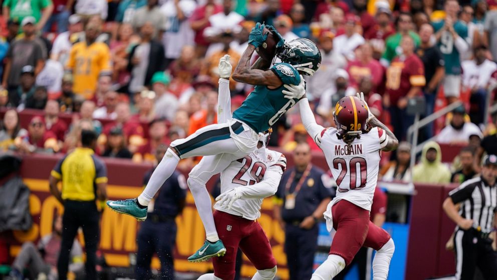 Philadelphia Eagles wide receiver DeVonta Smith (6) makes a catch against Washington Commanders cornerback Kendall Fuller (29) and safety Bobby McCain (20) during the first half of an NFL football game, Sunday, Sept. 25, 2022, in Landover, Md. (AP Ph