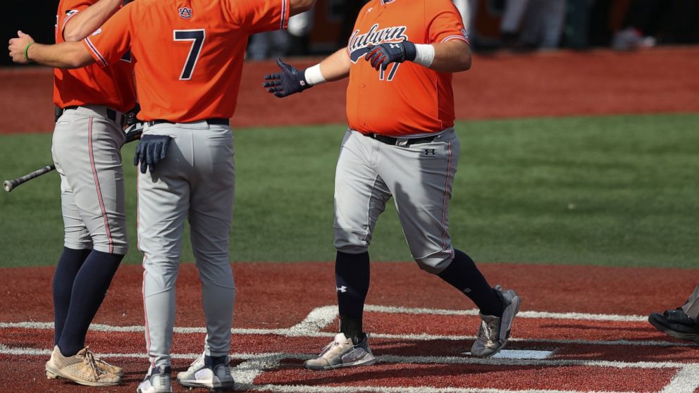 Auburn infielder Sonny DiChiara, right, celebrates with Cole Foster, center, and Bobby Peirce, left, after hitting a two-run home run during the third inning of an NCAA college baseball tournament super regional game against Oregon State on Monday, J
