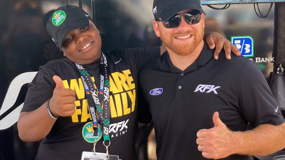 James Bromsey III, left, a sixth-grader at LeBron James' I Promise School in Akron, Ohio, poses with NASCAR driver Chris Buescher, Sunday, Aug. 7, 2022 in Brooklyn, Mich. Bromsey was given an all-access tour of Michigan International Speedway in Broo