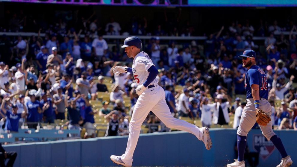 Los Angeles Dodgers' Freddie Freeman, left, rounds third after hitting a solo home run as Chicago Cubs third baseman Patrick Wisdom watches during the sixth inning of a baseball game Sunday, July 10, 2022, in Los Angeles. (AP Photo/Mark J. Terrill)