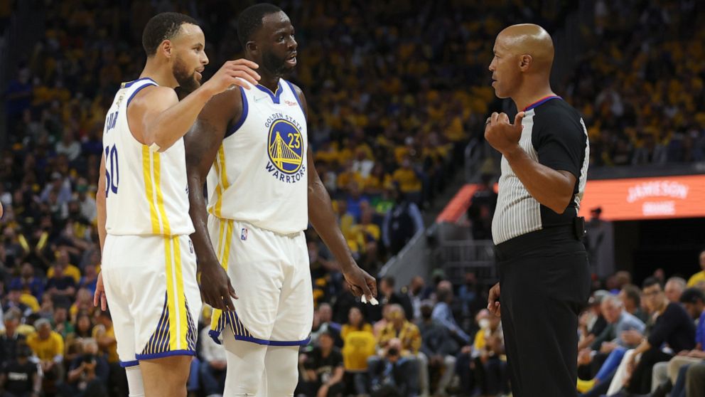 Golden State Warriors guard Stephen Curry, left, and forward Draymond Green (23) talk with referee Marc Davis during the second half of Game 1 of basketball's NBA Finals against the Boston Celtics in San Francisco, Thursday, June 2, 2022. (AP Photo/J