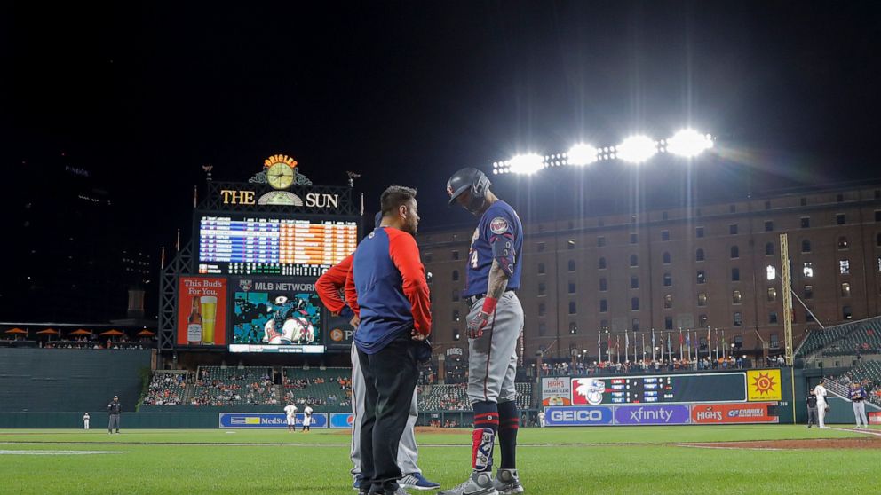 A trainer talks to Minnesota Twins' Carlos Correa, right, after he was hit by a pitch from Baltimore Orioles starting pitcher Spenser Watkins during the fifth inning of a baseball game, Thursday, May 5, 2022, in Baltimore. (AP Photo/Julio Cortez)
