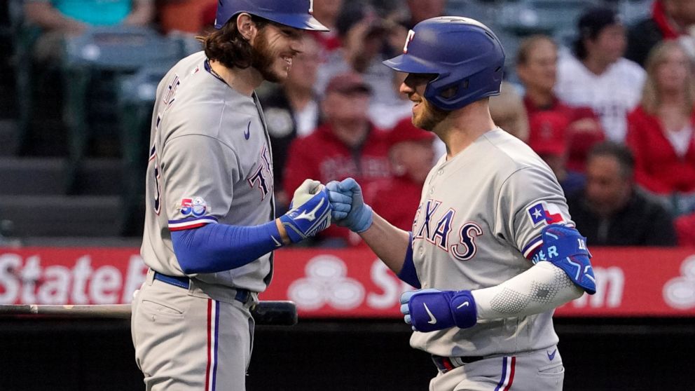 Texas Rangers' Mitch Garver, right, is congratulated by Jonah Heim after hitting a solo home run during the fourth inning of a baseball game against the Los Angeles Angels Wednesday, May 25, 2022, in Anaheim, Calif. (AP Photo/Mark J. Terrill)