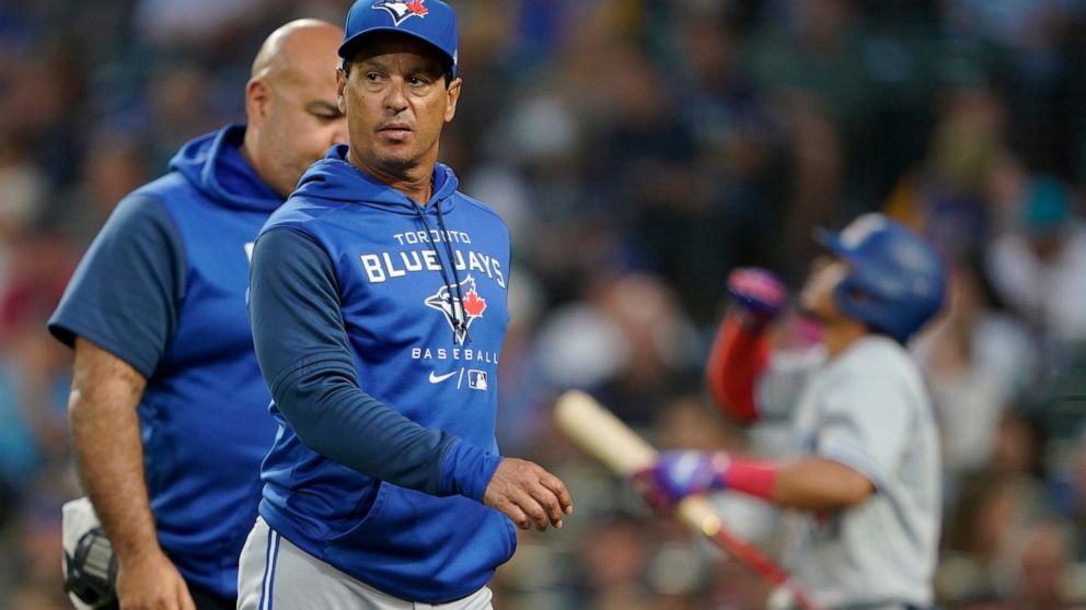 Toronto Blue Jays manager Charlie Montoyo walks with a trainer after Bradley Zimmer was hit by a pitch during the seventh inning of the team's baseball game against the Seattle Mariners, Thursday, July 7, 2022, in Seattle. Zimmer stayed in the game. 