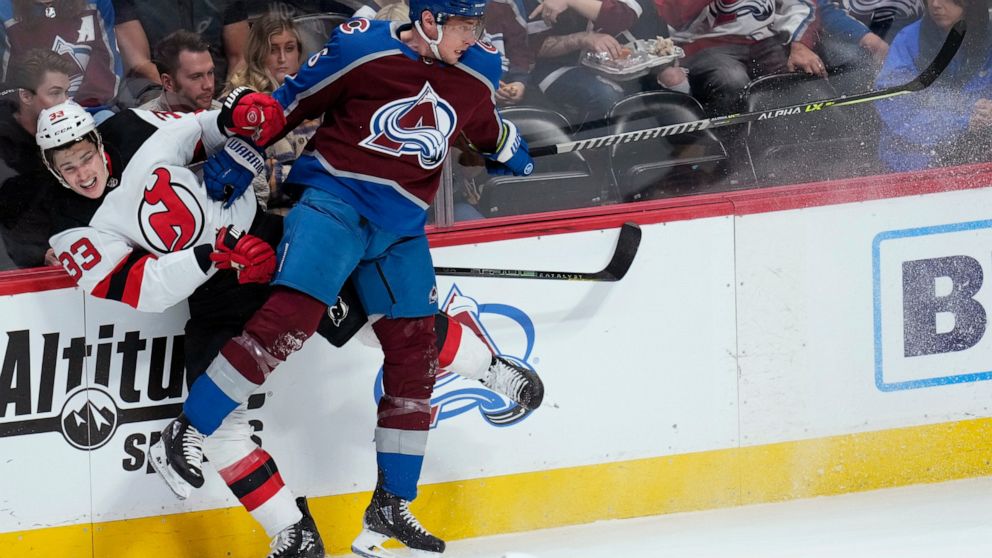 Colorado Avalanche defenseman Erik Johnson (6) checks New Jersey Devils defenseman Ryan Graves (33) into the boards during the first period of an NHL hockey game Thursday, April 14, 2022, in Denver. (AP Photo/Jack Dempsey)