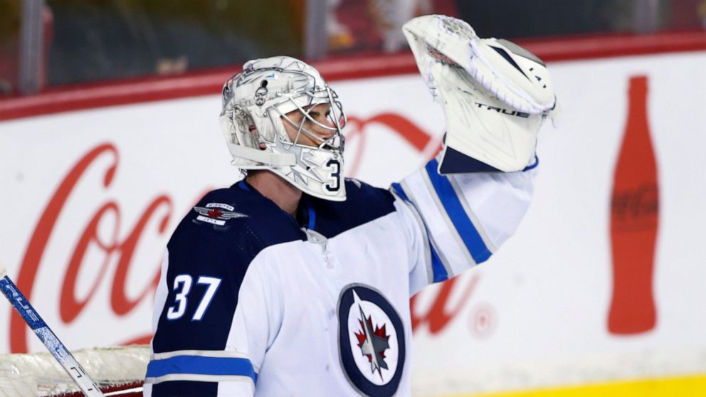 Winnipeg Jets goalie Connor Hellebuyck celebrates after the Jets scored an empty-net goal against the Calgary Flames during the third period of an NHL hockey game Saturday, Nov. 27, 2021, in Calgary, Alberta. (Larry MacDougal/The Canadian Press via AP)