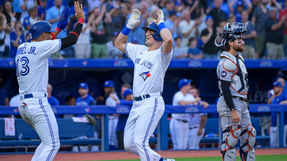 Toronto Blue Jays' Matt Chapman (26) celebrates with Lourdes Gurriel Jr. (13) as Detroit Tigers catcher Eric Haase stands near the plate after Chapman hit a two-run home run during fourth inning of a baseball game Thursday, July 28, 2022, in Toronto.