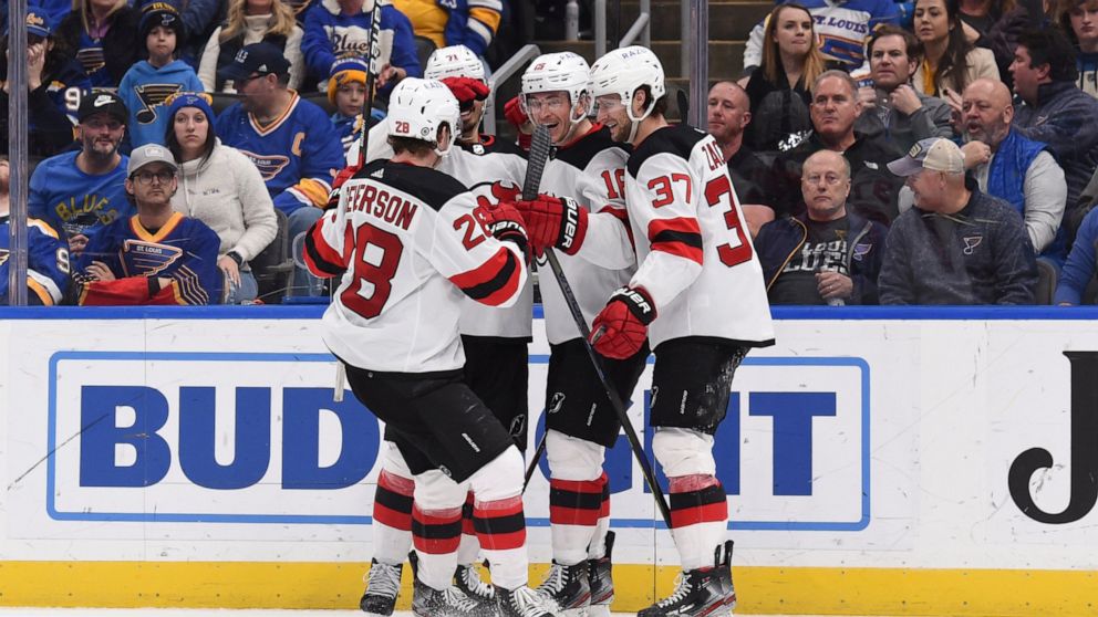 New Jersey Devils left wing Jimmy Vesey (16), center, is congratulated after scoring a goal against the St. Louis Blues during the third period of an NHL hockey game Thursday, Feb. 10, 2022, in St. Louis. (AP Photo/Joe Puetz)