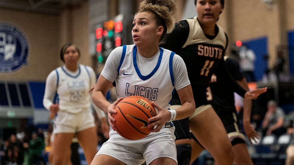 La Jolla Country Day high school point guard Jada Williams, center, drives to the basket during a basketball game Friday, Nov. 18, 2022, in Chatsworth, Calif. Williams’ videos of crazy basketball shots first got her noticed on social media and ultima