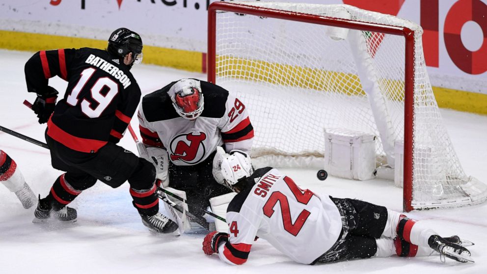 Ottawa Senators right wing Drake Batherson (19) scores on New Jersey Devils goaltender Mackenzie Blackwood (29) as Devils defenseman Ty Smith (24) sprawls on the ice during the overtime period of an NHL hockey game in Ottawa, on Tuesday, April 26, 20