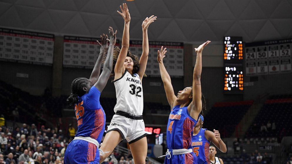 Central Florida's Brittney Smith, center, shoots between Florida's Faith Dut, left, and Florida's Zippy Broughton, right, during the first half of a first-round women's college basketball game in the NCAA tournament, Saturday, March 19, 2022, in Stor