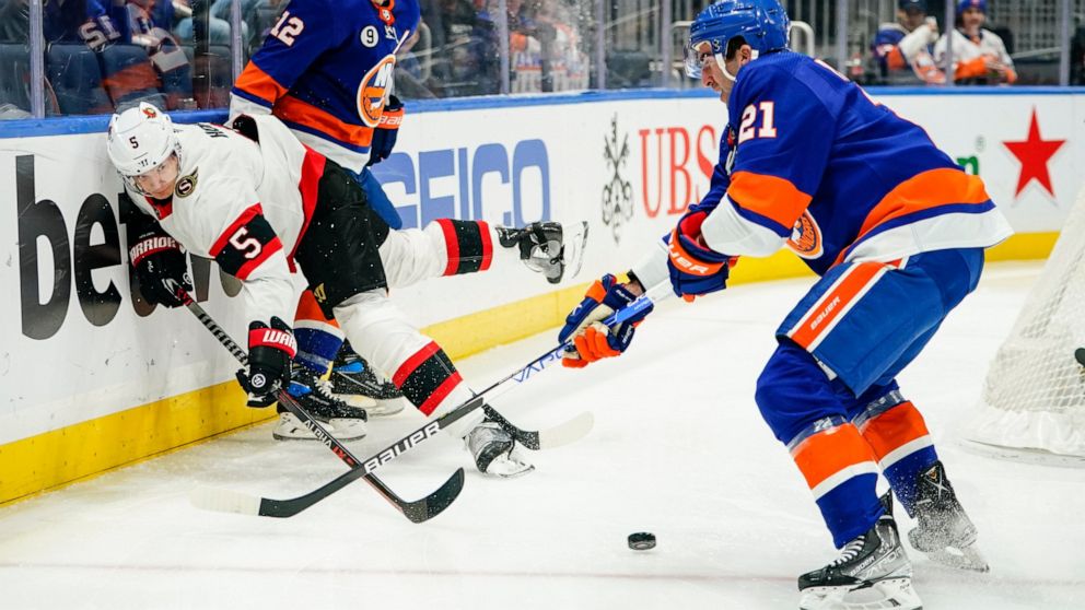 Ottawa Senators' Nick Holden (5) vies for control of the puck with New York Islanders' Josh Bailey (12) and Kyle Palmieri (21) during the second period of an NHL hockey game Tuesday, March 22, 2022, in Elmont, N.Y. (AP Photo/Frank Franklin II)