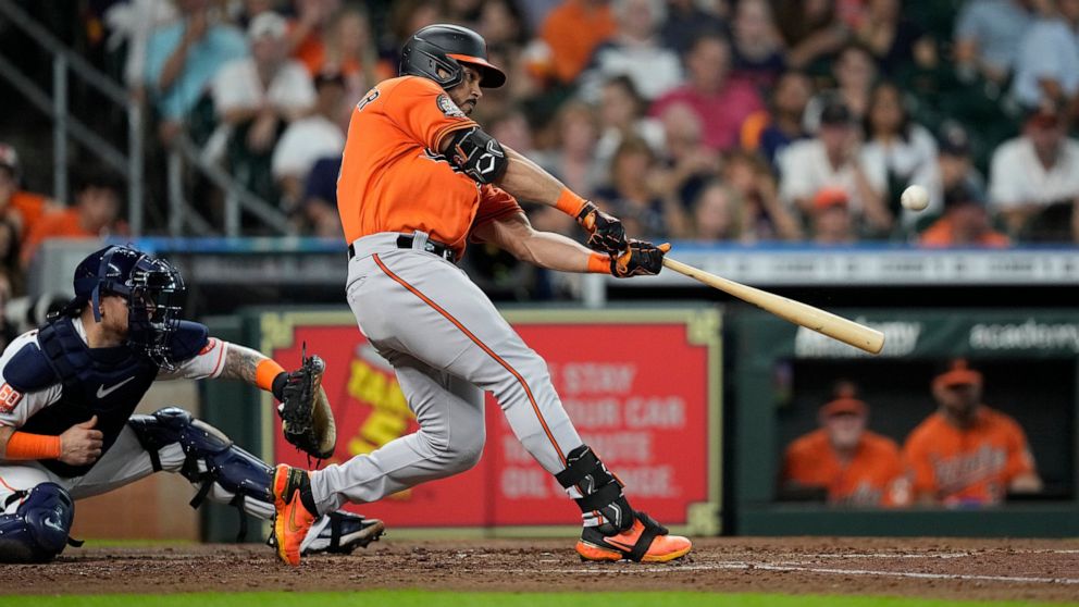 Baltimore Orioles' Anthony Santander, right, hits a two-run home run as Houston Astros catcher Christian Vazquez reaches for the pitch during the third inning of a baseball game Saturday, Aug. 27, 2022, in Houston. (AP Photo/David J. Phillip)