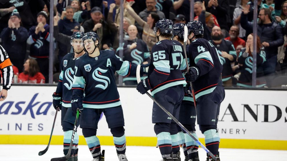 Seattle Kraken center Yanni Gourde, second from left, celebrates with center Jaden Schwartz, left, defenseman Jeremy Lauzon (55) and others after scoring the first of his two goals against the Detroit Red Wings during the third period of an NHL Hocke