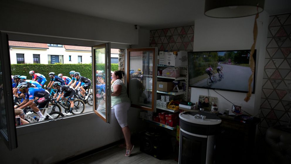 FILE - A woman cheers the riders, as she stands at her window, during the fourth stage of the Tour de France cycling race over 171.5 kilometers (106.6 miles) with start in Dunkerque and finish in Calais, France, Tuesday, July 5, 2022. (AP Photo/Danie
